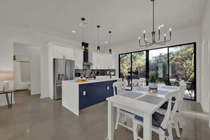 A modern kitchen with white cabinetry, a central island, and pendant lighting.