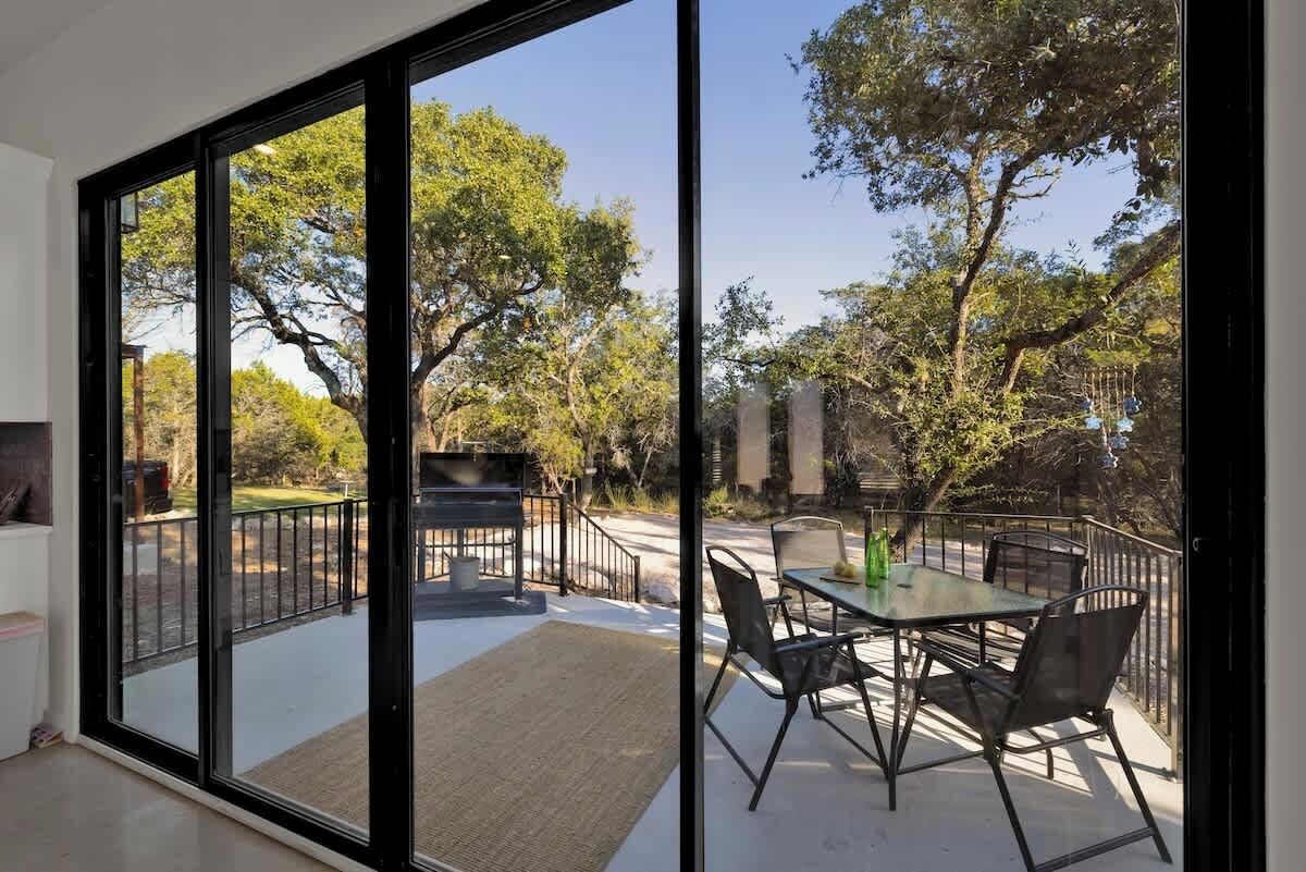 A modern outdoor patio with a glass door leading to a garden area.