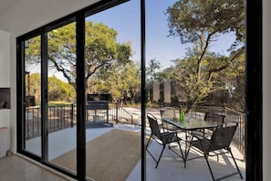 A modern outdoor patio with a glass door leading to a garden area. - Serene Guadalupe Getaway-River Access Nearby! (Spring Branch)
