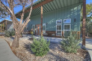 A building with a covered porch, a stone pathway, and small evergreen shrubs.