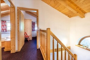 A wooden staircase leading to a lofted room with a window, a door, and a chair. - Authentic Mountain Retreat for 12 (Wald im Pinzgau)