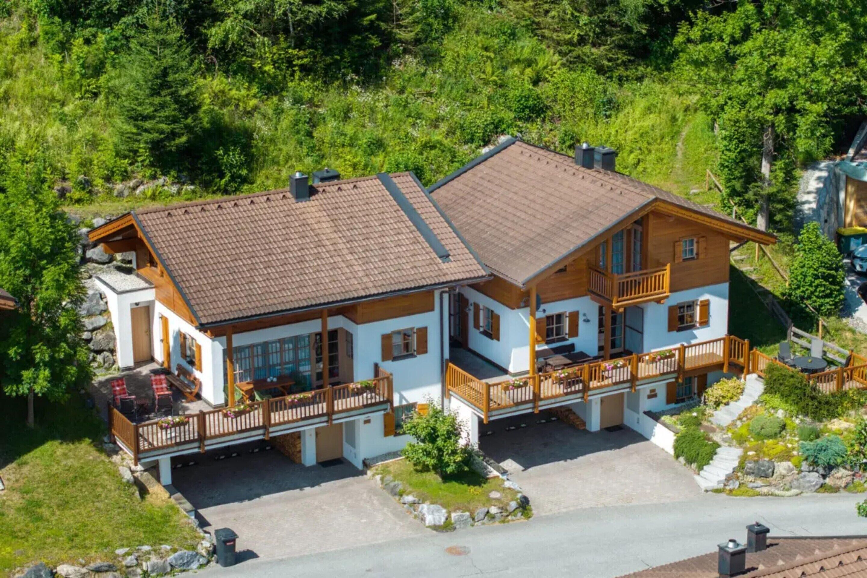 A two-story chalet with a sloped roof, wooden balconies, and a stone foundation.