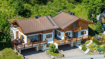 Eine zweistöckige Chalet mit geneigtem Dach, Holzbalkonen und einem Steinfundament.