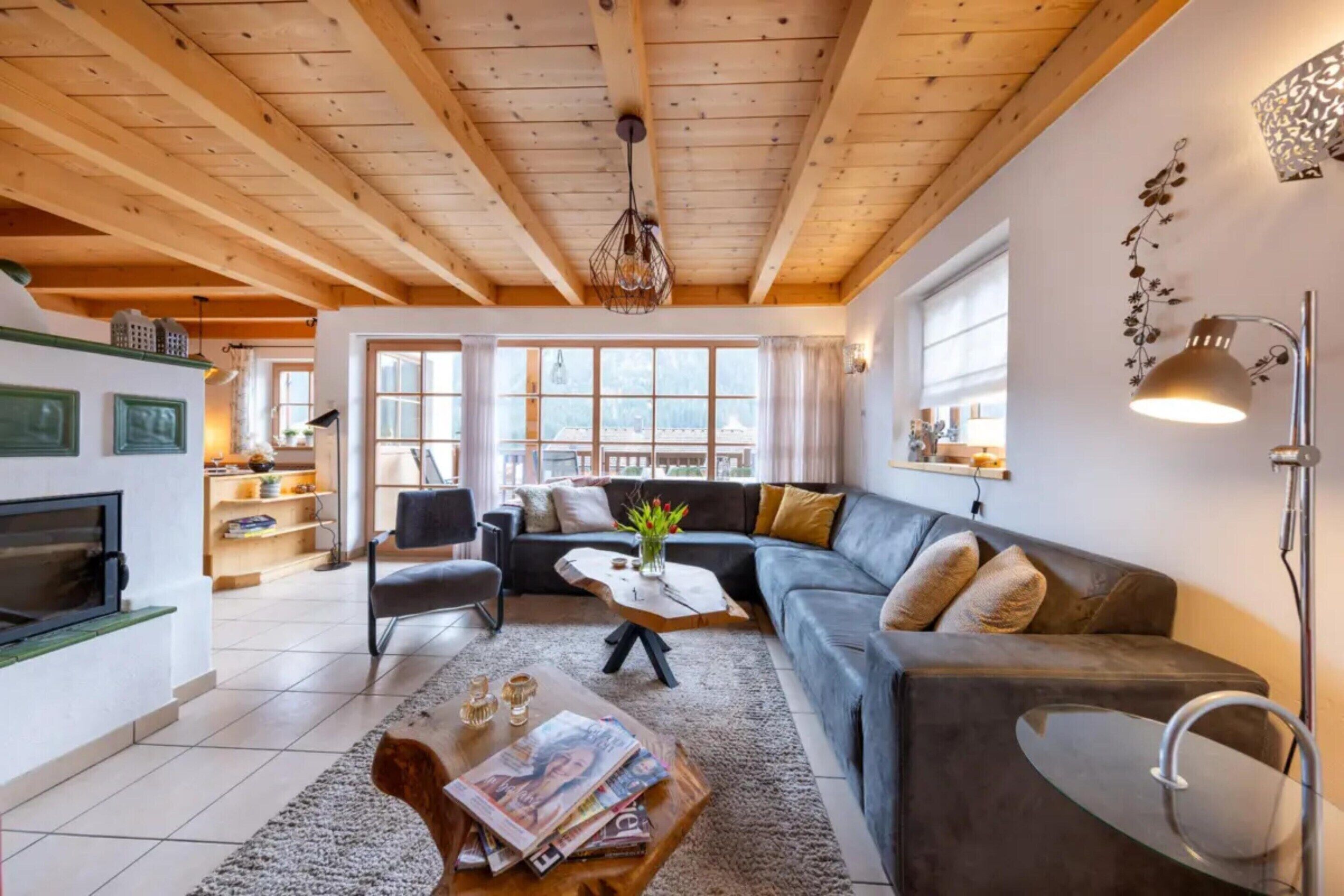 Un salon moderne avec un plafond en bois, un ensemble de canapés, une table basse et une cheminée.