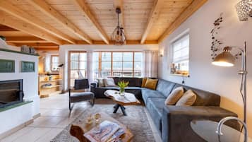 Un salon moderne avec un plafond en bois, un ensemble de canapés, une table basse et une cheminée.