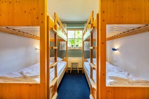 A room with bunk beds, a small table, and a window with a view of greenery. - Authentic Mountain Retreat for 12 (Wald im Pinzgau)