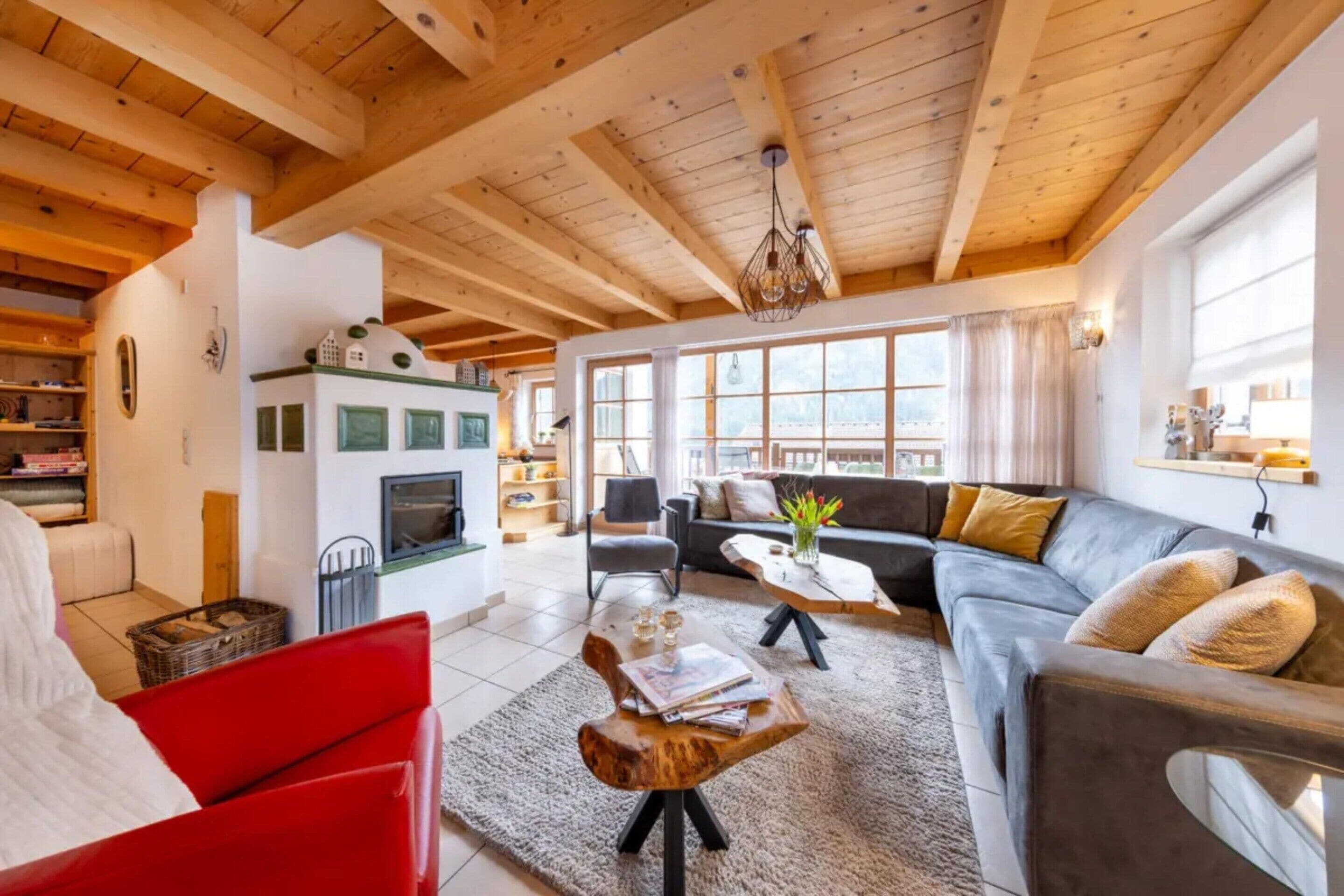A cozy living room with a fireplace, a sofa, a red chair, and a dining area with a table and chairs.
