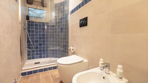 A bathroom with a shower, toilet, sink, and blue-tiled walls.