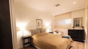 A bedroom with a bed, bedside tables, a dresser, a chair, and a mirror.