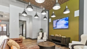 A modern lobby with leather sofas, a round coffee table, and pendant lighting. - The Melanie 1st Floor Condo with Pool & Gym Access (Tuscaloosa)