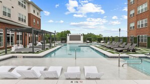 A swimming pool with lounge chairs and a covered seating area, surrounded by brick buildings. - The Melanie 1st Floor Condo with Pool & Gym Access (Tuscaloosa)