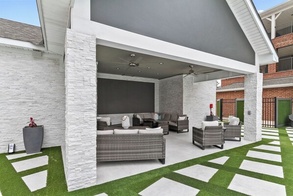 An outdoor patio with wicker furniture, a ceiling fan, and artificial grass. - The Kathleen Riverfront Condo with Pool & Gym Access (Tuscaloosa)