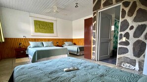 Una habitación con dos camas, un cabecero de madera, una pared de acento de piedra y un ventilador de techo.