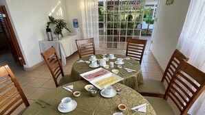 Comedor con mesas redondas dispuestas para el desayuno, con platos, tazas y cubiertos.