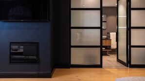 A modern room with a dark wall, a small window, and a sliding glass door leading to a bathroom.