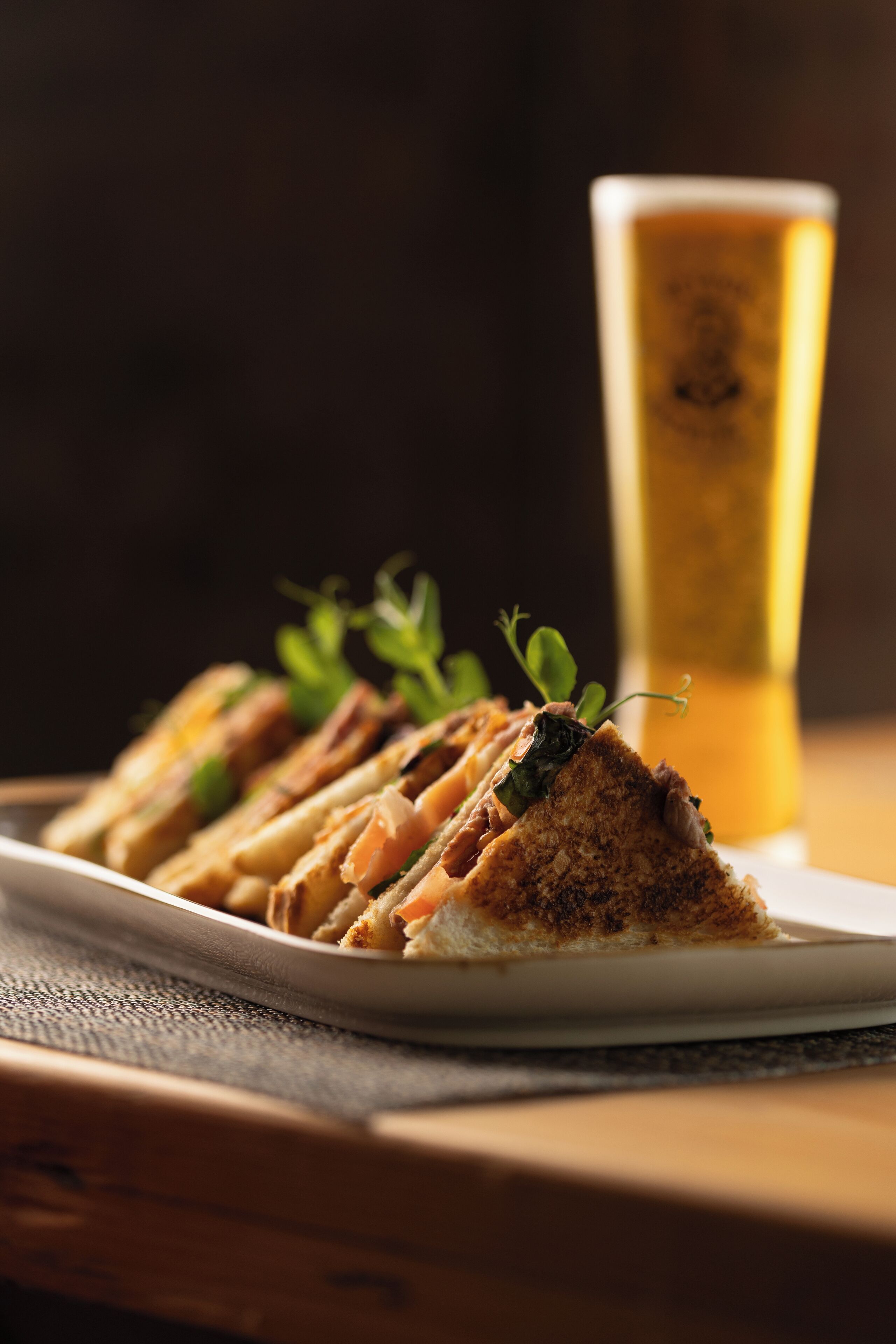 A plate of food with a glass of beer in the background.