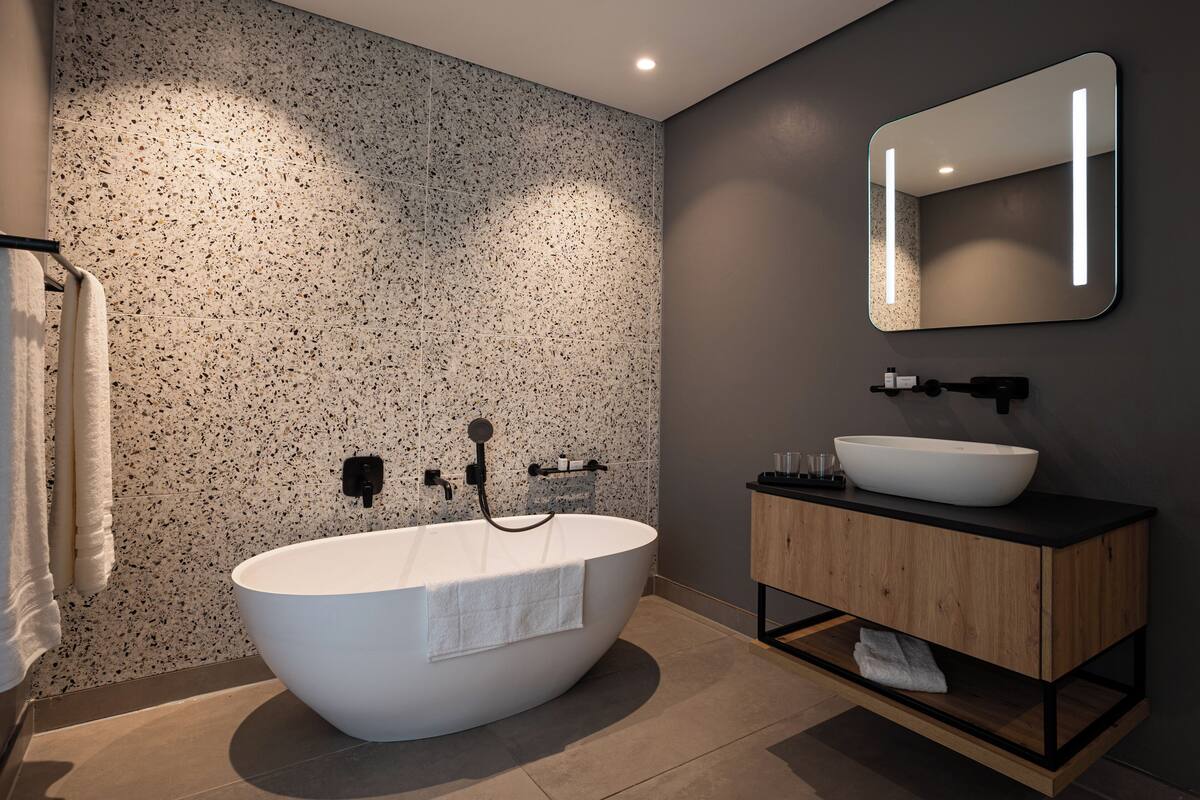 Ein modernes Badezimmer mit einer freistehenden Badewanne, einem Holzkosmetikschrank und einem großen Spiegel.