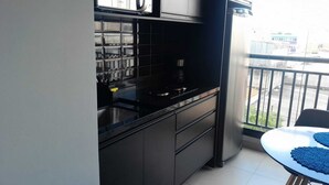 Een kleine keuken met zwarte kastjes, een roestvrijstalen spoelbak en een koffiezetapparaat.
