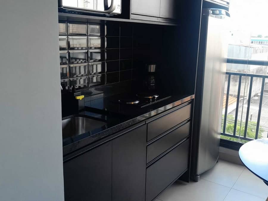 A compact kitchen with black cabinetry, a stainless steel sink, and a coffee maker.
