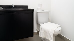 Een badkamer met een zwarte wastafel, een wit toilet en een handdoek aan de toilet.