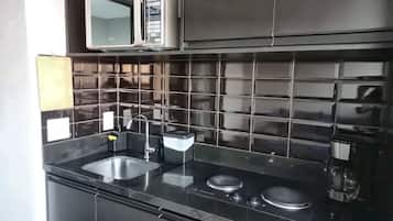 Una cucina moderna con piastrelle nere, elettrodomestici in acciaio inossidabile e un lavello a due vasche.