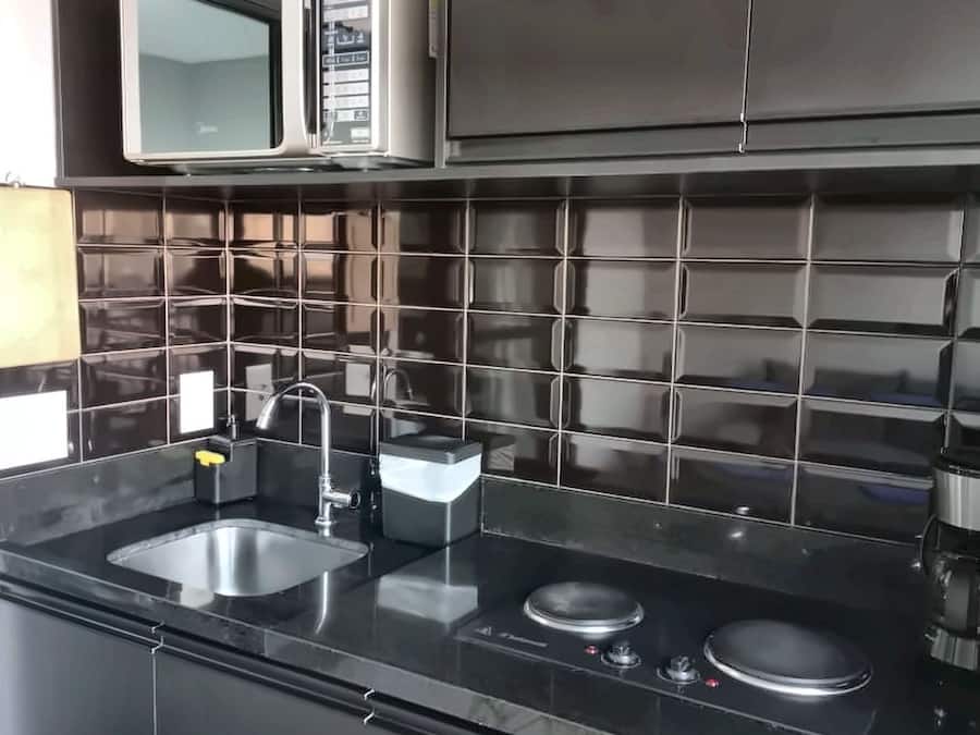 A modern kitchen with black tiles, stainless steel appliances, and a double sink.