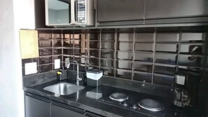 Een moderne keuken met zwarte tegels, roestvrijstalen apparatuur en een dubbele spoelbak.