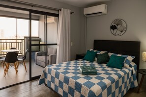 A hotel room with a checkered bedspread, a view to a balcony, and a wall-mounted air conditioner. - Elegance Suítes Anhembi (São Paulo)