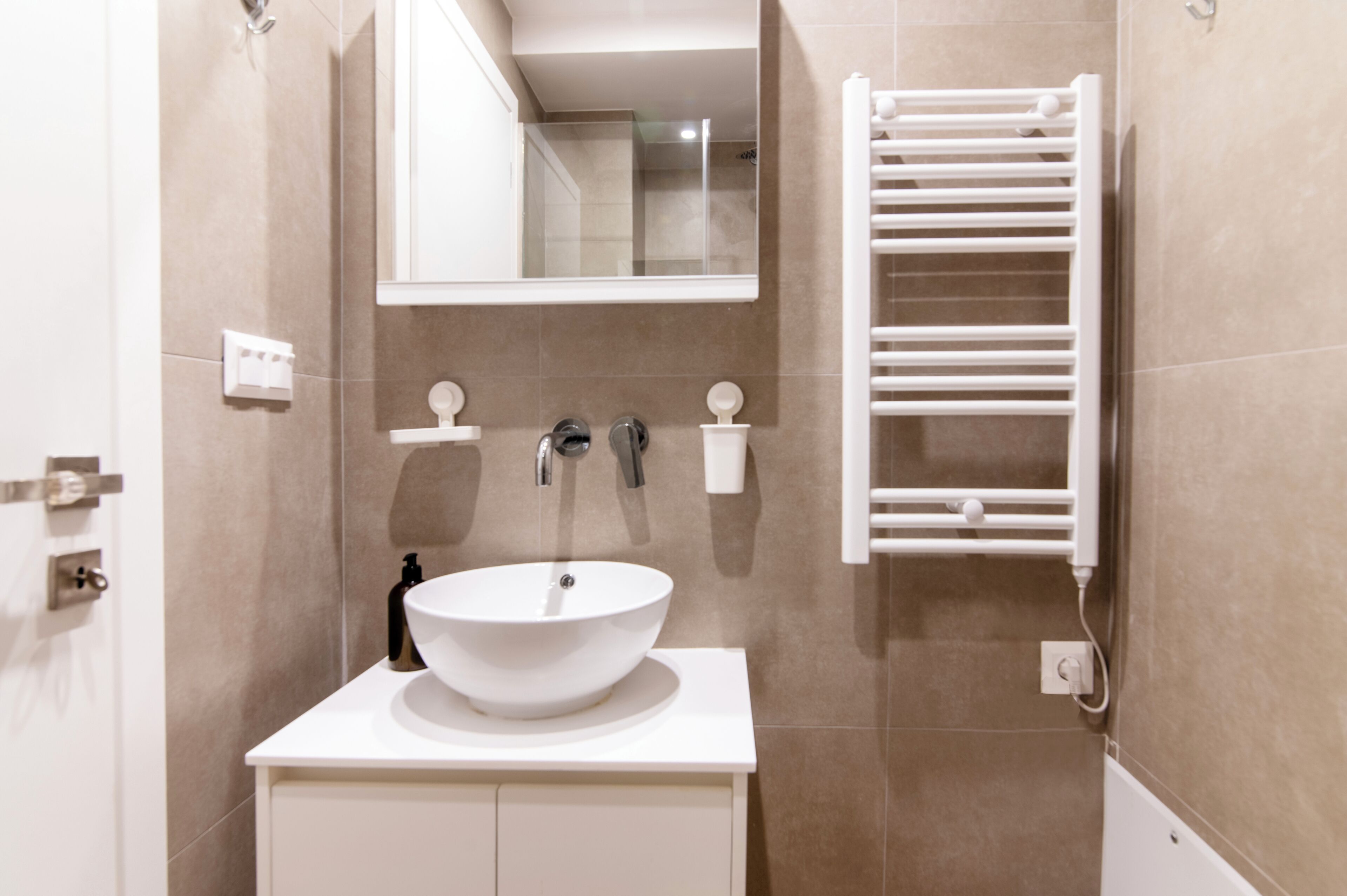 A modern bathroom with a white sink, a mirror, and a towel rack.