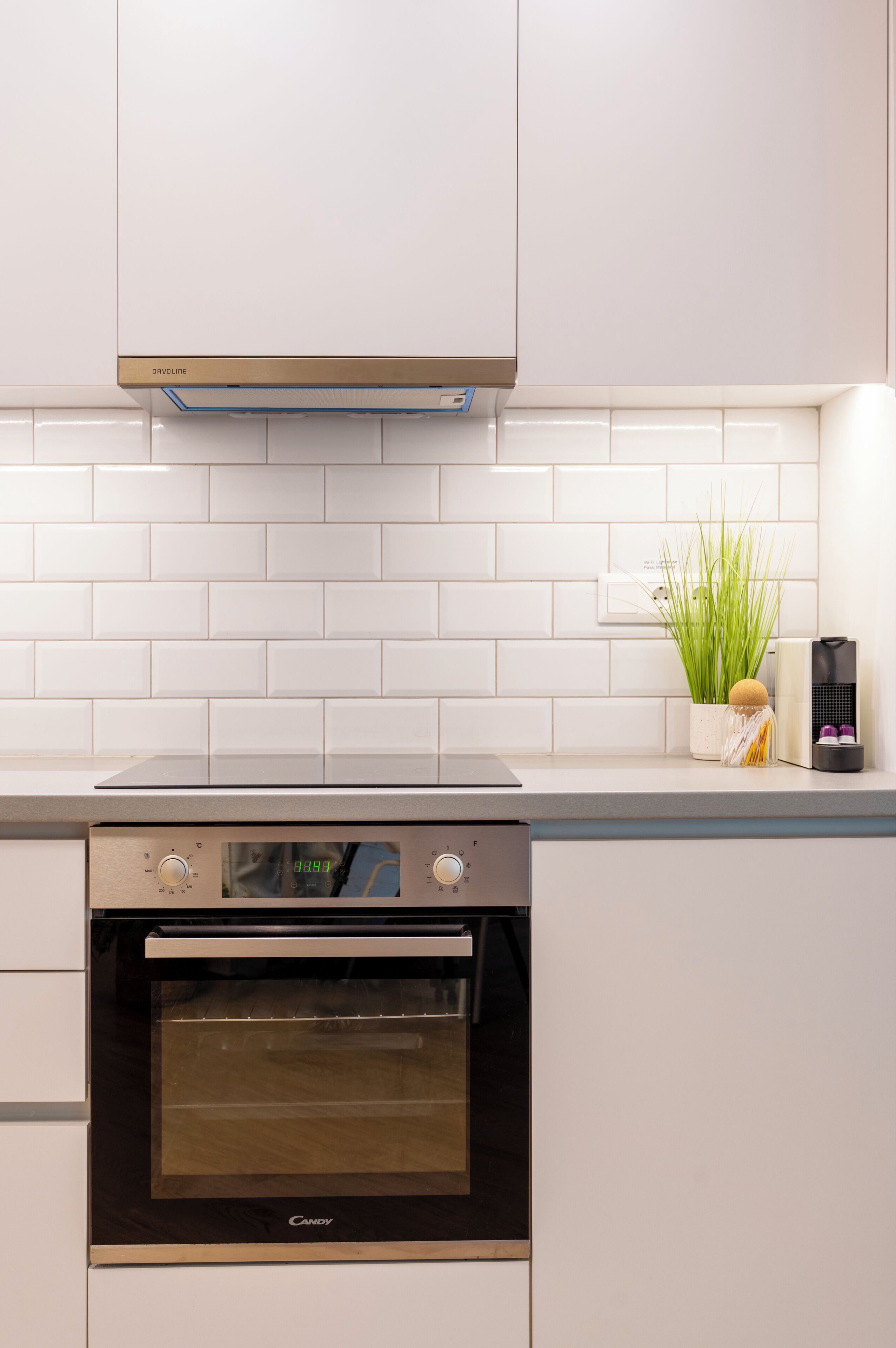 A kitchen with white cabinets, a built-in oven, and a backsplash.