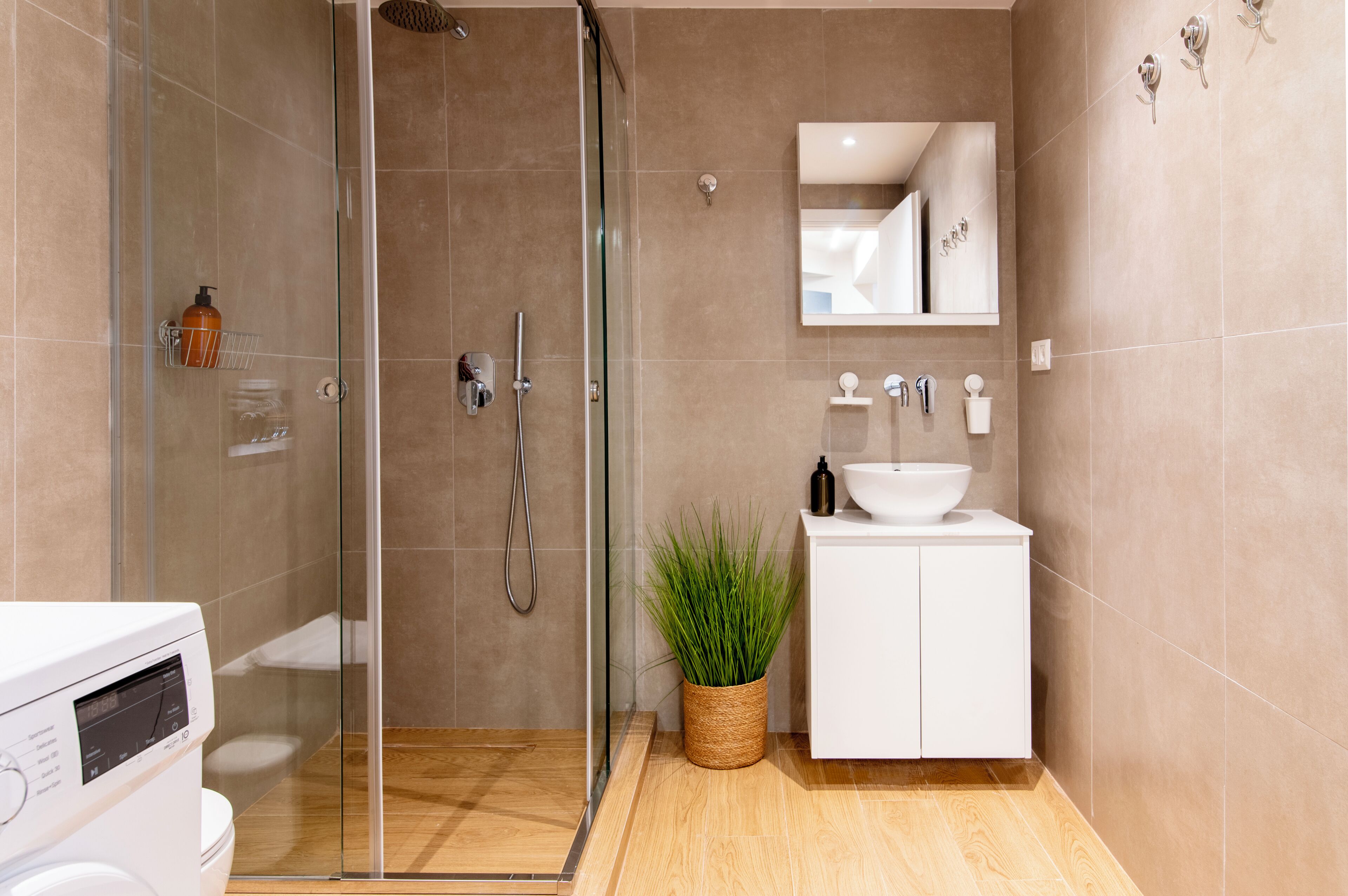 A modern bathroom with a glass-enclosed shower, a white sink, and a mirror above it.