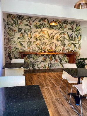 A restaurant with a tropical leaf-patterned wall, wooden flooring, and modern seating. - Pousada Cardeal Mota (Santana do Riacho)