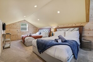 A bedroom with two beds, a wooden ceiling, and a small table.