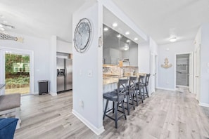 Une cuisine moderne avec un îlot central, des tabourets de bar et une horloge au mur.