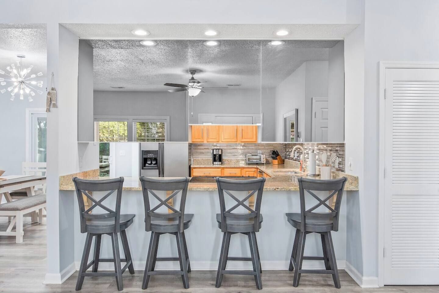 A modern kitchen with a bar area, featuring a ceiling fan, built-in appliances, and a large window.