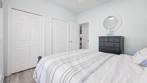 Une chambre à coucher avec un lit, une commode, un ventilateur de plafond et une porte.