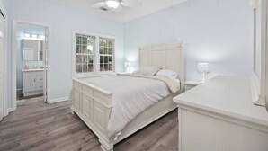 A bedroom with a bed, a nightstand, a dresser, a window, and a ceiling fan.