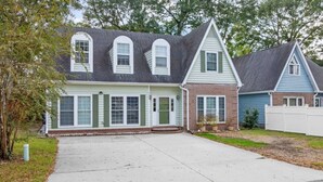 A two-story house with a front porch, a garage, and a fenced yard.