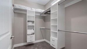 Un dressing avec des portes ouvertes, des étagères et une tringle à vêtements.