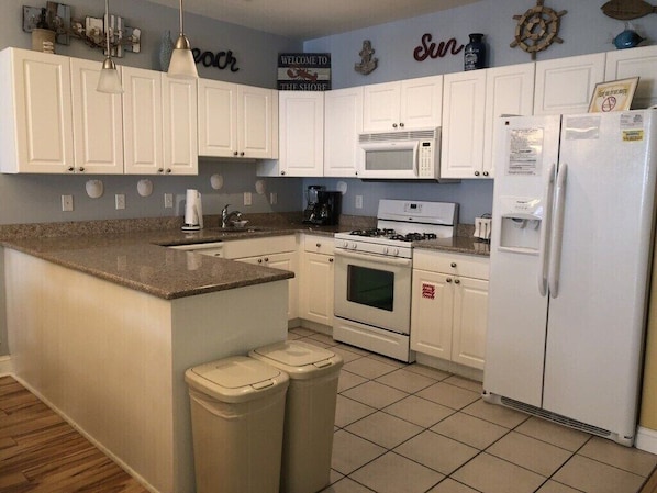 Welcome to the Shore, where a fully equipped kitchen awaits with a central island, microwave, stove, oven, and refrigerator.