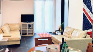 Appartamento Deluxe, balcone, vista città | Area soggiorno | TV a schermo piatto 32 pollici con canali via cavo