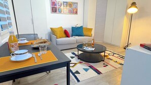 A modern living room with a sofa, coffee table, and a dining table with breakfast items.