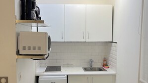 A compact kitchen with white cabinets, a built-in sink, and a small refrigerator.