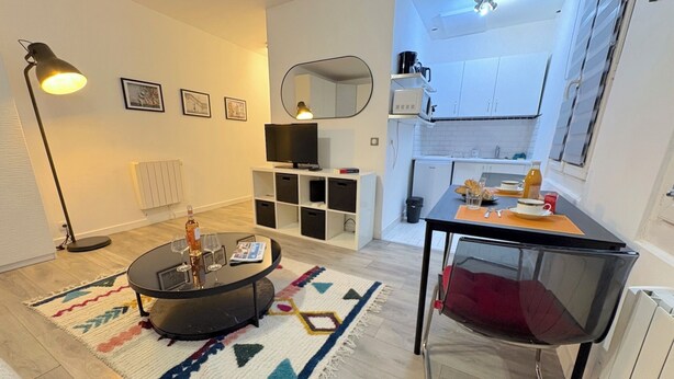 A modern living room with a round coffee table, a TV, and a dining area with a table and chairs.