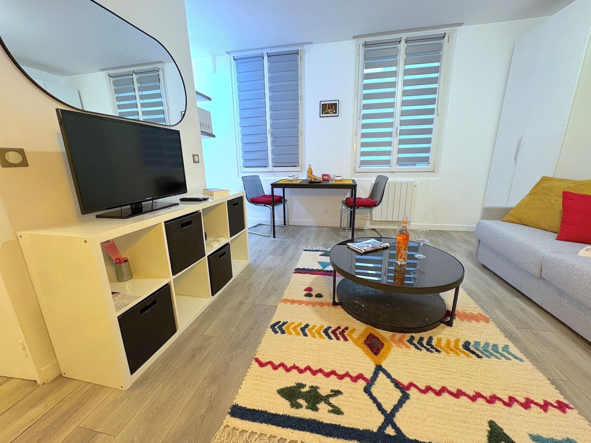 Un salon avec un téléviseur, un canapé, une table basse et un tapis.