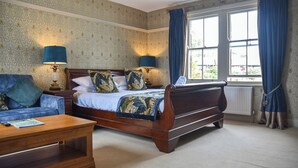 Een slaapkamer met een groot bed, een houten nachtkastje, een blauwe bank en een houten salontafel.