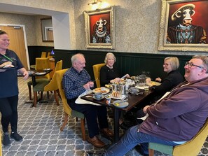 Un espace repas avec une table dressée pour quatre personnes, un serveur et un mur orné d’un motif.