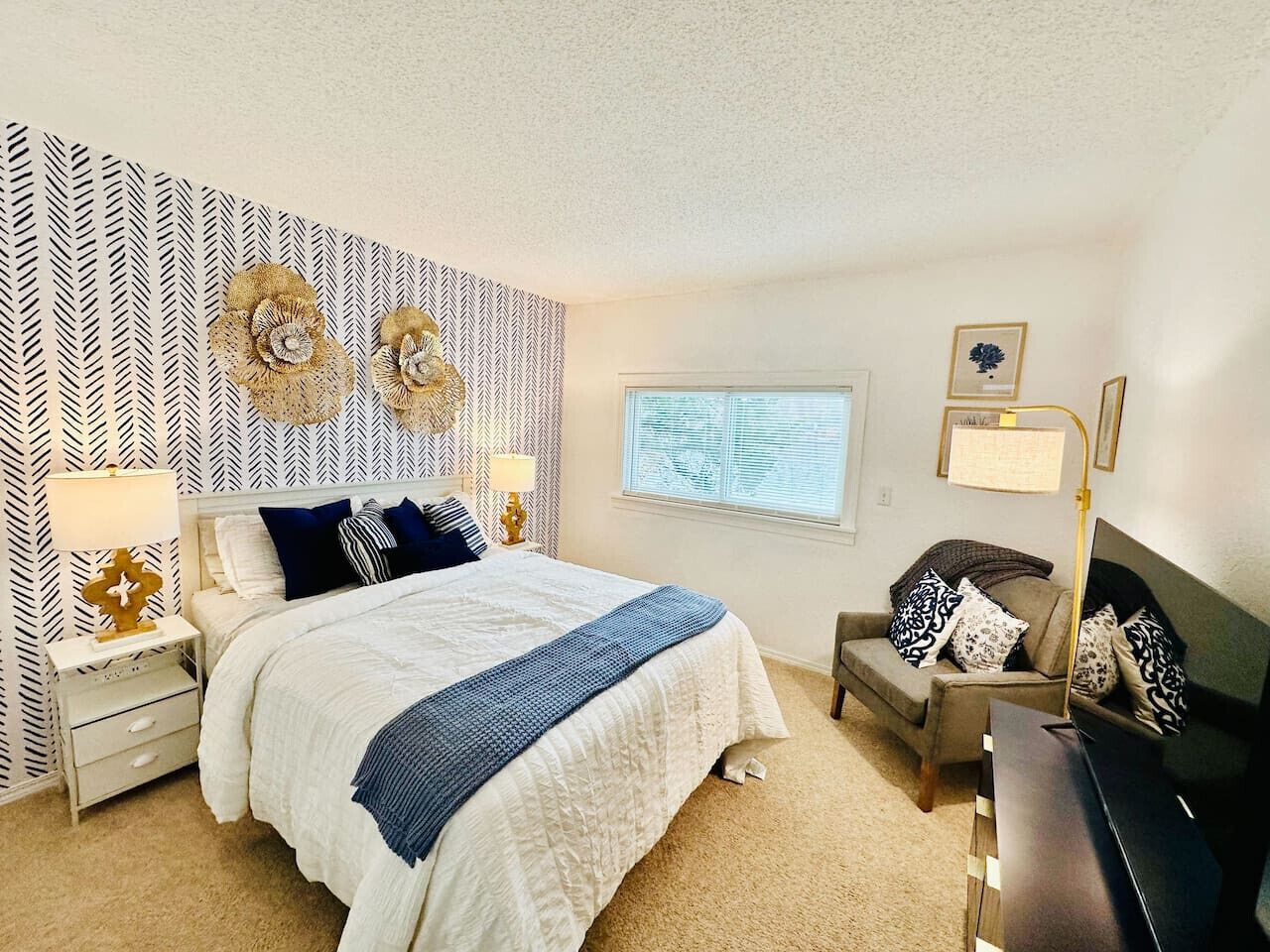 A bedroom with a bed, nightstands, a dresser, a chair, and a window.