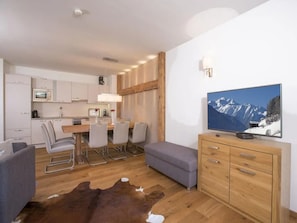 Una sala de estar moderna con un televisor de pantalla plana, un mueble de madera y un comedor con sillas y una mesa.