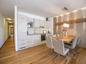 Una cocina moderna con armarios blancos, una mesa de comedor de madera y una araña.